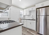 Thumbnail 1 of 10 - a kitchen with white cabinets and a stainless steel refrigerator at Huntington Manor Homes Apartment, California