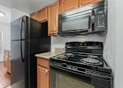 Thumbnail 33 of 52 - A black refrigerator and microwave in a kitchen.