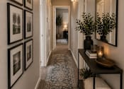 Thumbnail 9 of 38 - A hallway with a table, vases, and framed pictures on the wall.