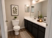 Thumbnail 13 of 38 - A white toilet sits in a bathroom with a framed leaf picture on the wall.