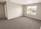 Thumbnail 16 of 38 - A room with a carpeted floor and a window showing a parking lot outside.