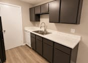 Thumbnail 22 of 38 - A kitchen with a white countertop and brown cabinets.