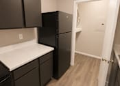Thumbnail 23 of 38 - A black refrigerator in a kitchen with brown cabinets.