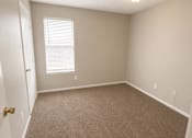 Thumbnail 25 of 38 - A room with a carpeted floor and a window with blinds.
