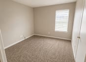 Thumbnail 26 of 38 - A room with a carpeted floor and a window with blinds.