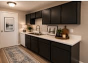 Thumbnail 7 of 38 - A kitchen with black cabinets and a white countertop.