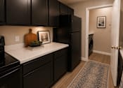 Thumbnail 8 of 38 - A kitchen with black cabinets and a white countertop.