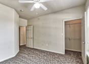 Thumbnail 6 of 16 - A bedroom with a closet and a ceiling fan in Arlington, TX.