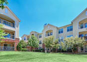 Thumbnail 15 of 16 - Apartment complex with green lawn and trees at Addison Park Apartments in Arlington, TX.