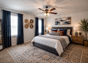 Thumbnail 21 of 52 - A bedroom with a large bed and a ceiling fan.