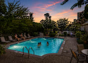 Thumbnail 7 of 52 - A swimming pool surrounded by trees and people enjoying the water.