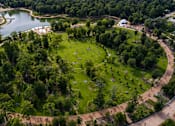 Thumbnail 51 of 52 - A park with a large pond and a grassy area with people walking around.