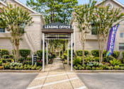 Thumbnail 46 of 52 - A leasing office is surrounded by a landscaped area with a welcome sign.