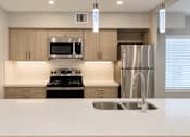 Thumbnail 25 of 52 - A modern kitchen with a stainless steel refrigerator and a white countertop.