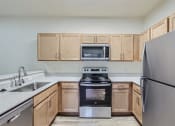 Thumbnail 48 of 51 - Fairview, OR Apartments - Lodges at Lake Salish - Kitchen with Sleek Light Tan Cabinetry, Stainless Steel Appliances, and a Built-In Breakfast Bar