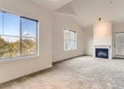 Thumbnail 17 of 51 - Fairview, OR Apartments for Rent - Lodges at Lake Salish - Living Room with Plush Carpet, an Electric Fireplace, and Large Windows