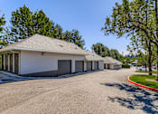 Thumbnail 27 of 34 - A white building with a grey roof and a parking lot in front.
