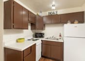 Thumbnail 16 of 17 - A kitchen with brown cabinets and white appliances.