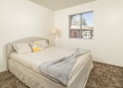 Thumbnail 16 of 17 - A bedroom with a bed, pillows, a blanket, a lamp, and a picture of a house on the wall.