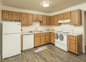 Thumbnail 12 of 17 - A kitchen with wooden cabinets and white appliances.