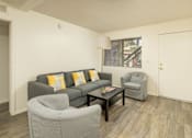 Thumbnail 15 of 17 - A living room with a grey couch, a grey armchair, and a black coffee table.
