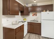 Thumbnail 15 of 20 - A kitchen with brown cabinets and a white fridge.