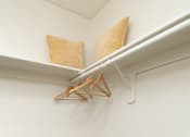 Thumbnail 14 of 20 - A white shelf with two pillows and a hanger on it.