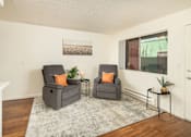 Thumbnail 9 of 22 - Two grey chairs with orange pillows are in a room with a grey rug.