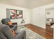 Thumbnail 8 of 22 - A living room with a grey couch and a small table.