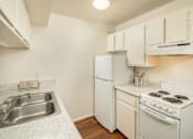 Thumbnail 11 of 22 - A small kitchen with a white stove and a white refrigerator.