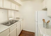 Thumbnail 12 of 22 - A kitchen with white cabinets and a white fridge.