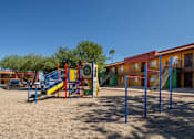 Thumbnail 19 of 22 - A playground with a slide and swings in front of a building.