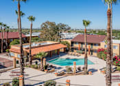 Thumbnail 3 of 13 - A pool surrounded by palm trees and benches.