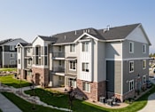 Thumbnail 42 of 45 - A large, modern apartment building with a well-maintained lawn in front.