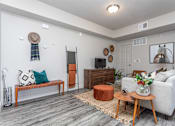 Thumbnail 2 of 45 - A living room with a white couch, a wooden coffee table, and a rug on the floor.