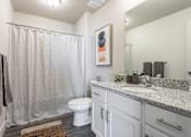 Thumbnail 6 of 45 - A bathroom with a toilet, sink, and shower curtain.