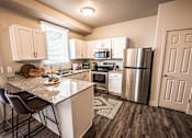 Thumbnail 18 of 45 - A kitchen with a granite countertop and stainless steel appliances.