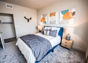 Thumbnail 24 of 45 - A bedroom with a bed, nightstand, and a painting on the wall.