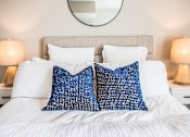 Thumbnail 28 of 45 - A bed with white sheets and two blue patterned pillows.