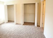 Thumbnail 6 of 10 - A room with three open closets and a carpeted floor.