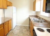 Thumbnail 9 of 10 - A kitchen with brown cabinets and a white fridge.