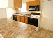 Thumbnail 8 of 10 - A kitchen with a granite countertop and wooden cabinets.