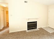 Thumbnail 7 of 10 - A living room with a fireplace and a carpet.