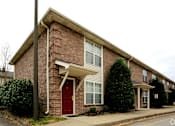 Thumbnail 3 of 10 - A red door is on the left side of a brick house.