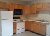 Thumbnail 2 of 10 - A kitchen with wooden cabinets and white appliances.