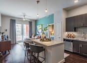 Thumbnail 3 of 35 - Luxury apartment kitchen with granite countertops, stainless steel appliances, tile backsplash, and oversized island with seating