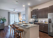 Thumbnail 4 of 35 - Luxury apartment kitchen with granite countertops, stainless steel appliances, tile backsplash, and oversized island with seating