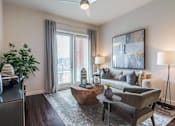 Thumbnail 8 of 35 - Modern apartment living room with comfortable seating, large windows, wood-style flooring, and abundant natural light.