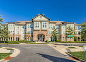 Thumbnail 12 of 26 - A large, modern building with a stone facade and a green lawn in front.