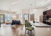 Thumbnail 2 of 26 - A modern kitchen with a dining area and a living room.